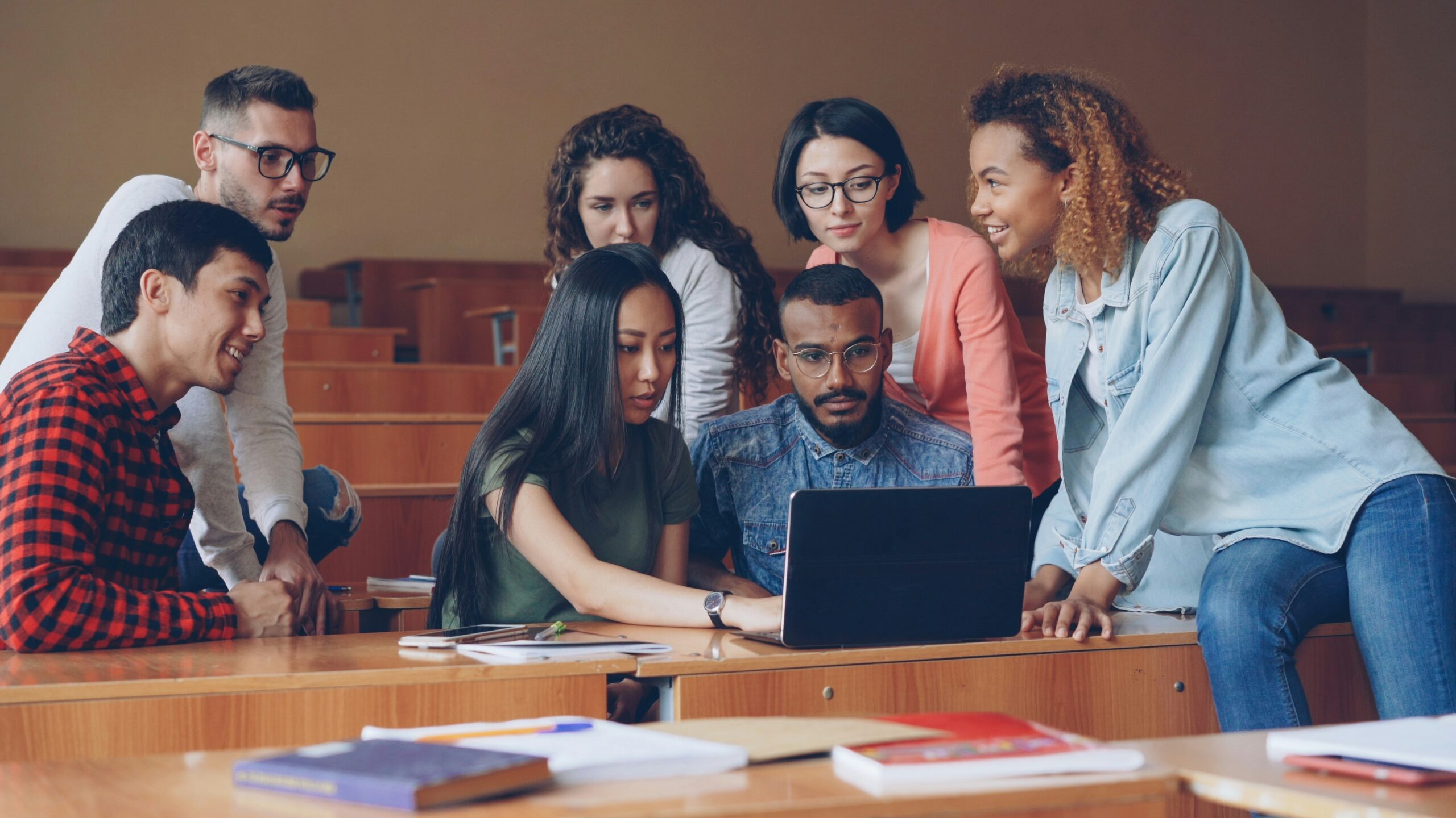 Diverse students collaborating around a laptop